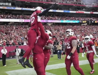 Arizona Cardinals offensive tackle Paris Johnson Jr. (70) lifts wide receiver Marvin Harrison Jr. (18) after his second touchdown catch against the Los Angeles Rams at State Farm Stadium.